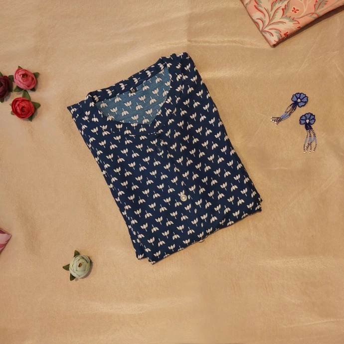 a shirt and a pair of earrings on a bed